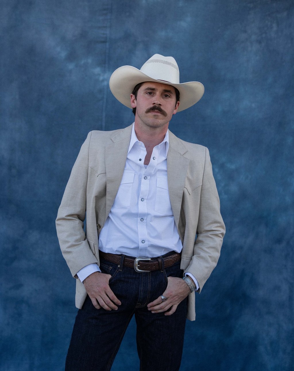 Stetson Western campaign: man with groomed mustache in white cowboy hat and beige blazer